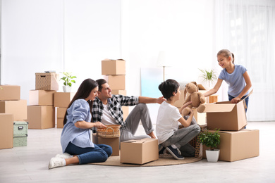 Happy family unpacking moving boxes at their new home