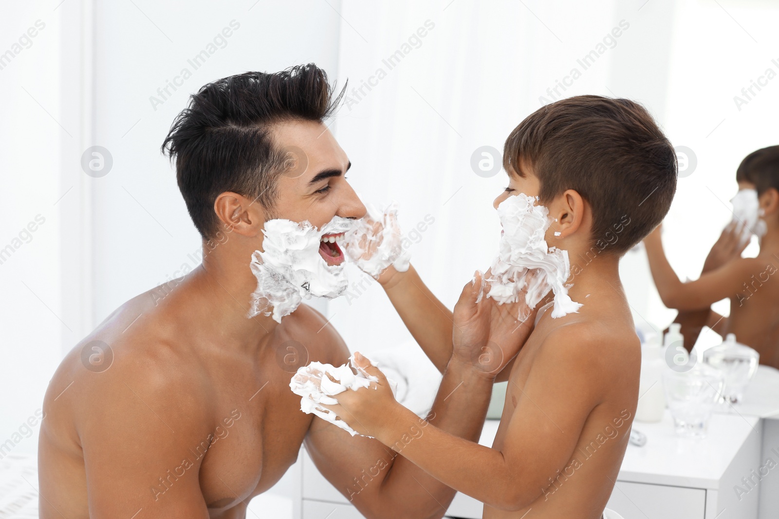 Photo of Father and son having fun while applying shaving foam in bathroom