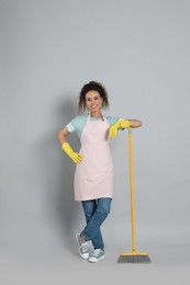 African American woman with yellow broom on grey background