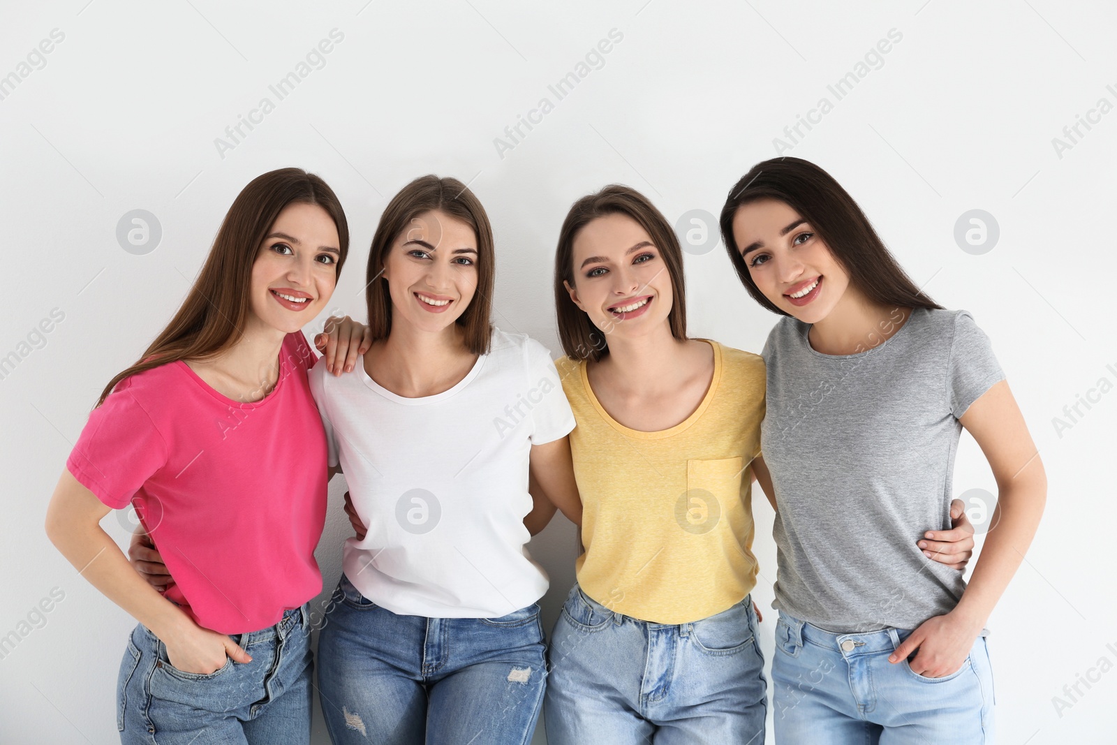 Photo of Beautiful young ladies in jeans and colorful t-shirts on white background. Woman's Day