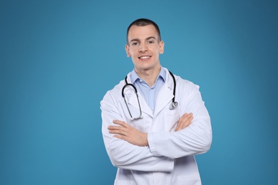 Photo of Young man in white coat with stethoscope on color background