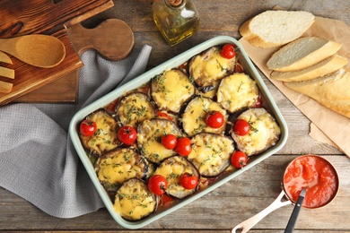 Photo of Flat lay composition with baked eggplant, tomatoes and cheese in dishware on wooden table