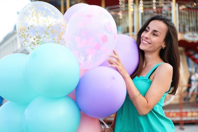 Photo of Attractive young woman with color balloons near carousel