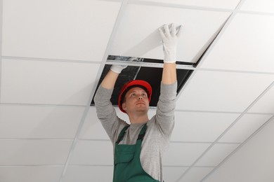 Photo of Suspended ceiling installation. Builder working with PVC tile