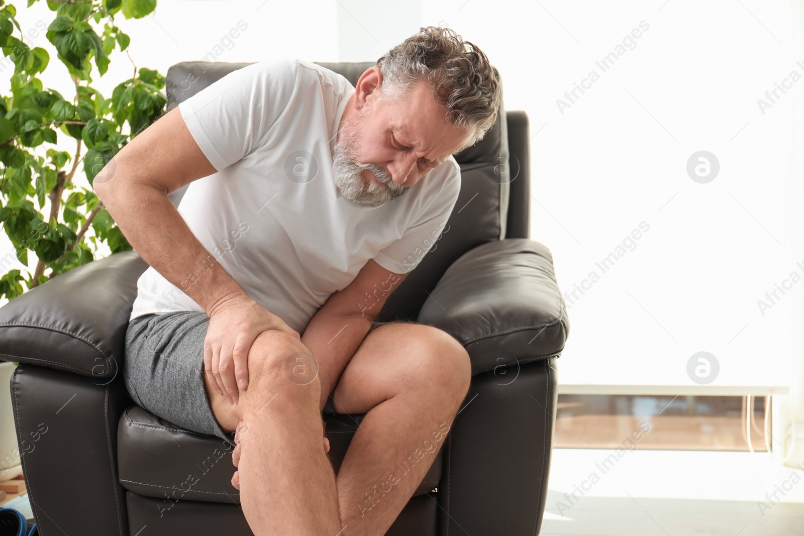 Photo of Senior man suffering from knee pain indoors