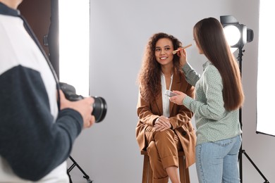 Photo of Professional photographer and makeup artist with model in studio