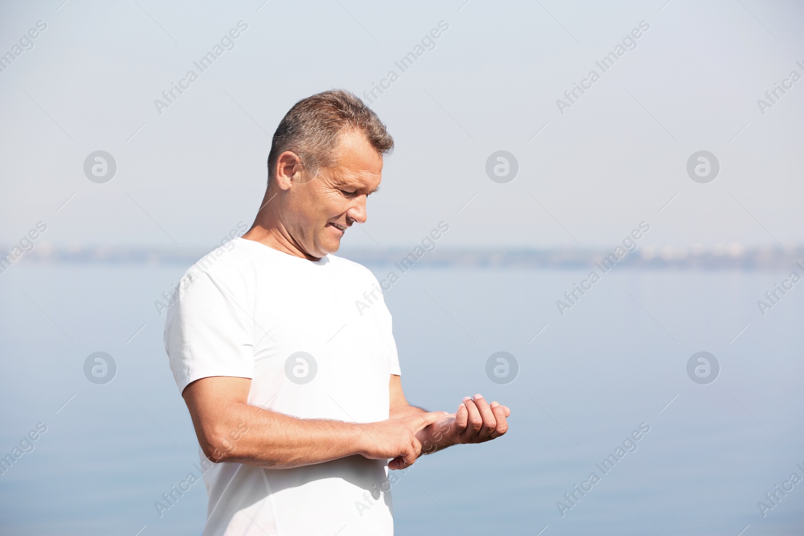 Photo of Man checking pulse outdoors on sunny day