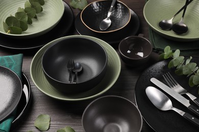 Stylish table setting with cutlery and eucalyptus branches on dark wooden background