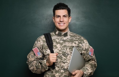 Photo of Cadet with backpack and laptop near chalkboard. Military education