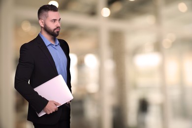 Successful lawyer with laptop on blurred background, space for text