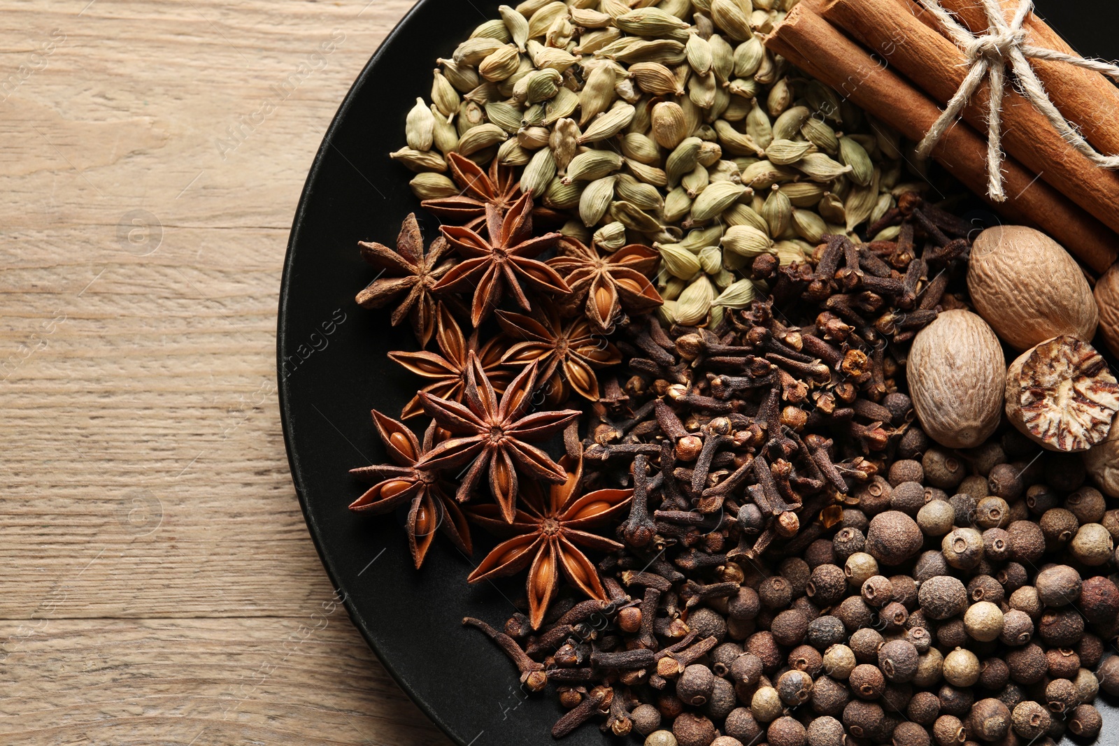 Photo of Different spices and nuts on wooden table, top view