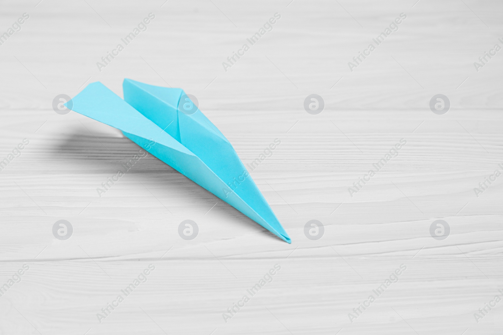 Photo of Handmade paper plane on white wooden table. Space for text