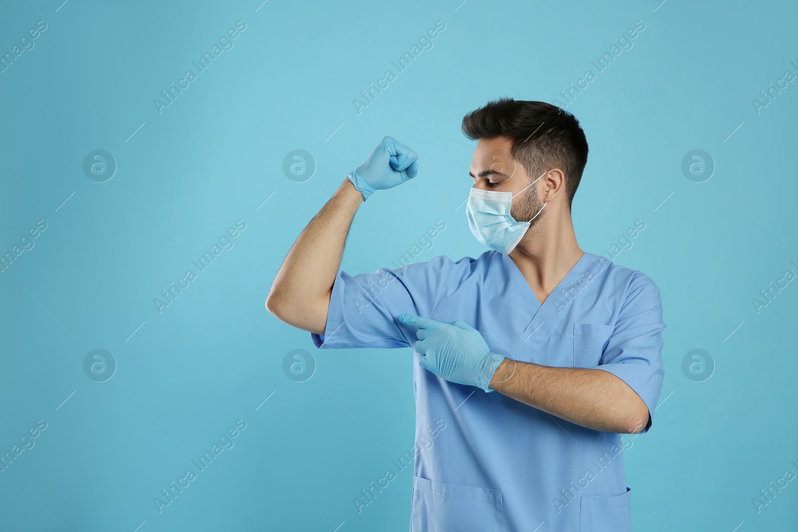 Photo of Doctor with protective mask and gloves showing muscles on light blue background, space for text. Strong immunity concept