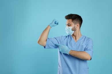 Photo of Doctor with protective mask and gloves showing muscles on light blue background, space for text. Strong immunity concept