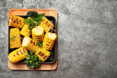 Photo of Tasty grilled corn on grey table, top view. Space for text