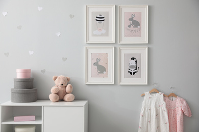 Stylish baby room interior with chest of drawers and cute pictures on wall