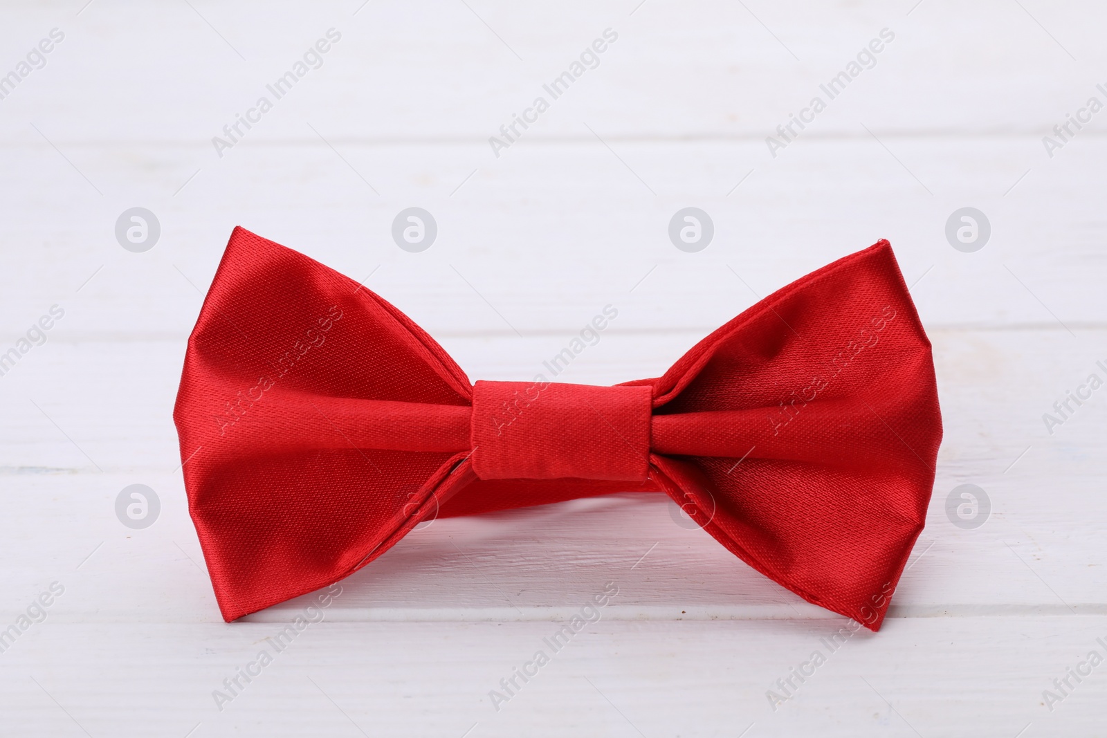 Photo of Stylish red bow tie on white wooden table