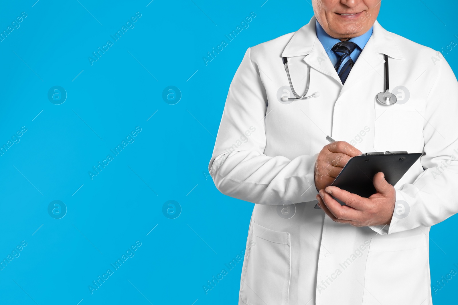 Photo of Senior doctor with clipboard on light blue background, closeup. Space for text