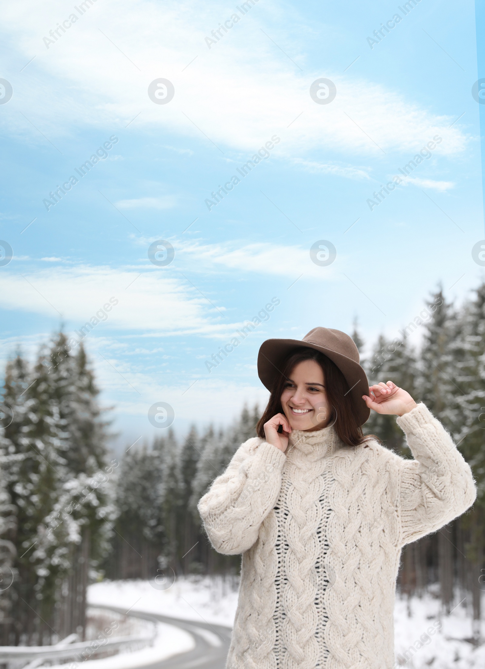 Photo of Young woman in warm sweater near snowy forest. Winter vacation