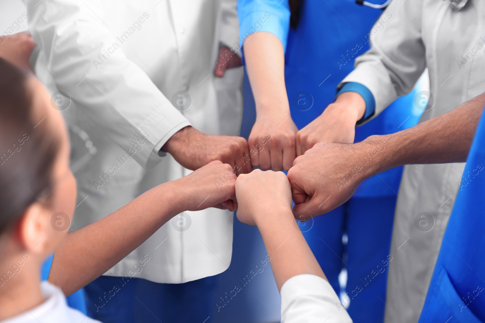 Photo of Team of medical doctors putting hands together indoors, closeup