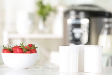 Cups for homemade yogurt and fresh strawberry on table in kitchen. Recipe for multi cooker