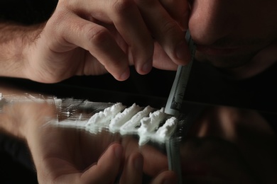 Photo of Drug addict taking cocaine at table, closeup view