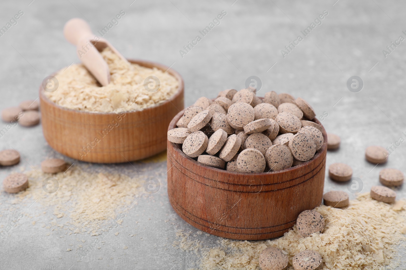 Photo of Brewer's yeast flakes and tablets on grey table, closeup