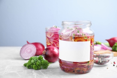 Photo of Jars of pickled onions with blank label on marble table