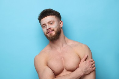 Handsome man with facial mask on his face against light blue background