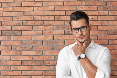 Portrait of handsome young man and space for text on brick wall background