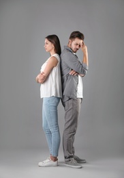 Photo of Upset young couple on grey background. Relationship problems