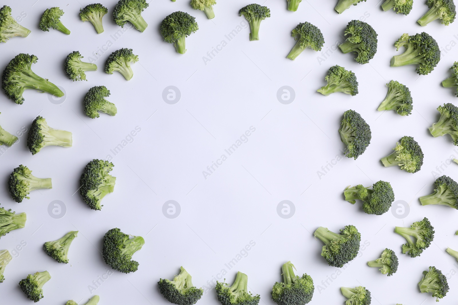 Photo of Frame made of many fresh green broccoli pieces on white background, flat lay. Space for text