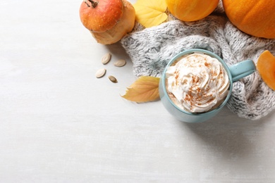 Flat lay composition with cup of pumpkin spice latte, autumn decor and space for text on light table