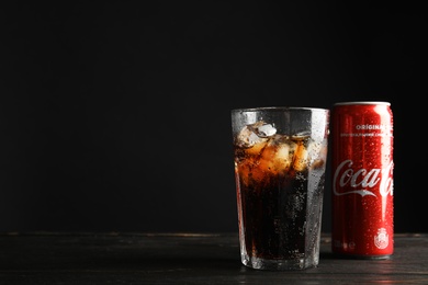 Photo of MYKOLAIV, UKRAINE - NOVEMBER 15, 2018: Glass and can with Coca Cola on table against black background. Space for text