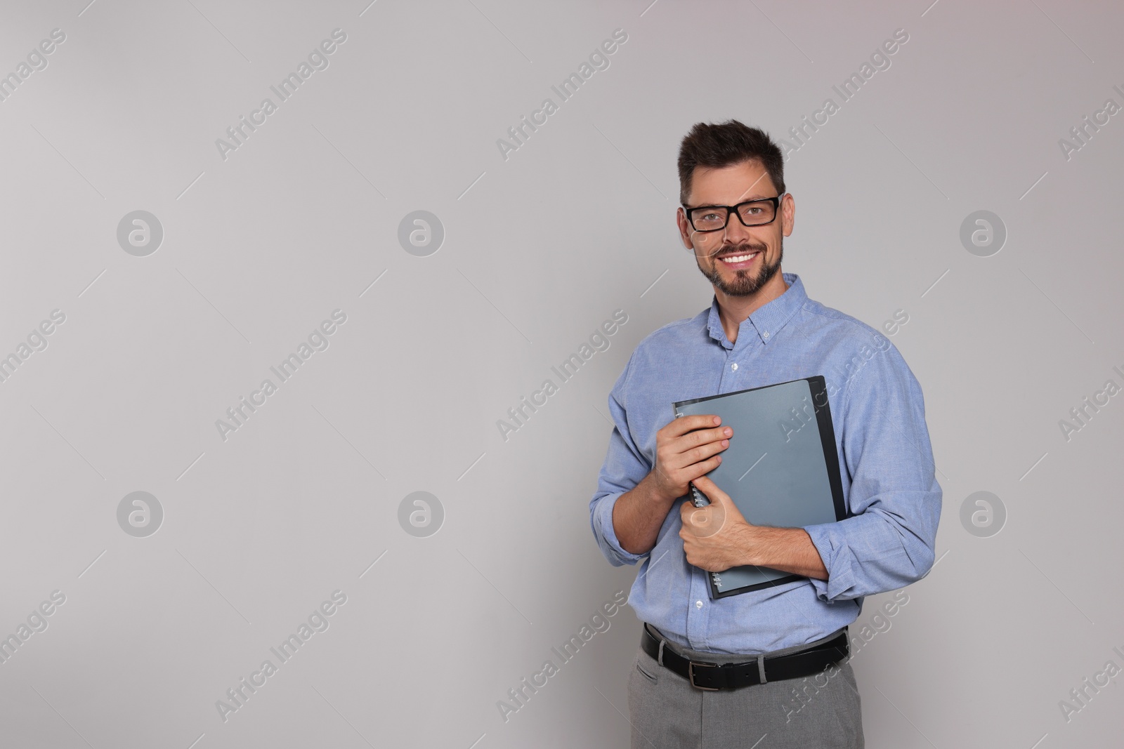 Photo of Happy teacher with glasses and stationery against beige background. Space for text