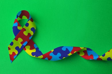 World Autism Awareness Day. Colorful puzzle ribbon on green background, top view