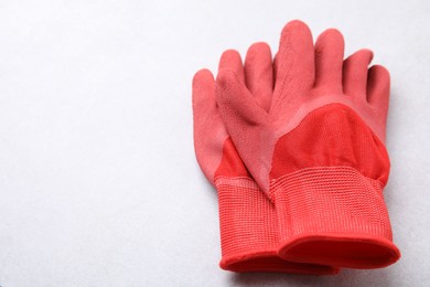 Photo of Pair of red gardening gloves on light grey table, space for text
