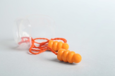 Pair of orange ear plugs with cord on white background