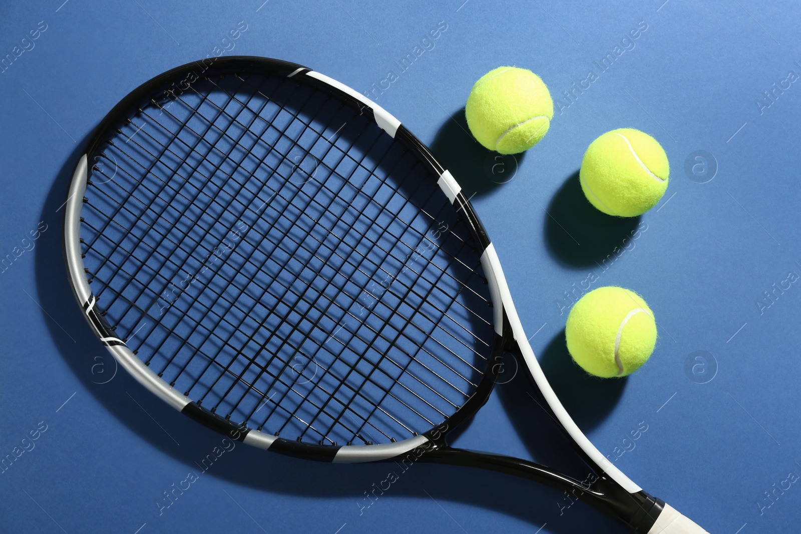 Photo of Tennis racket and balls on blue background, flat lay. Sports equipment
