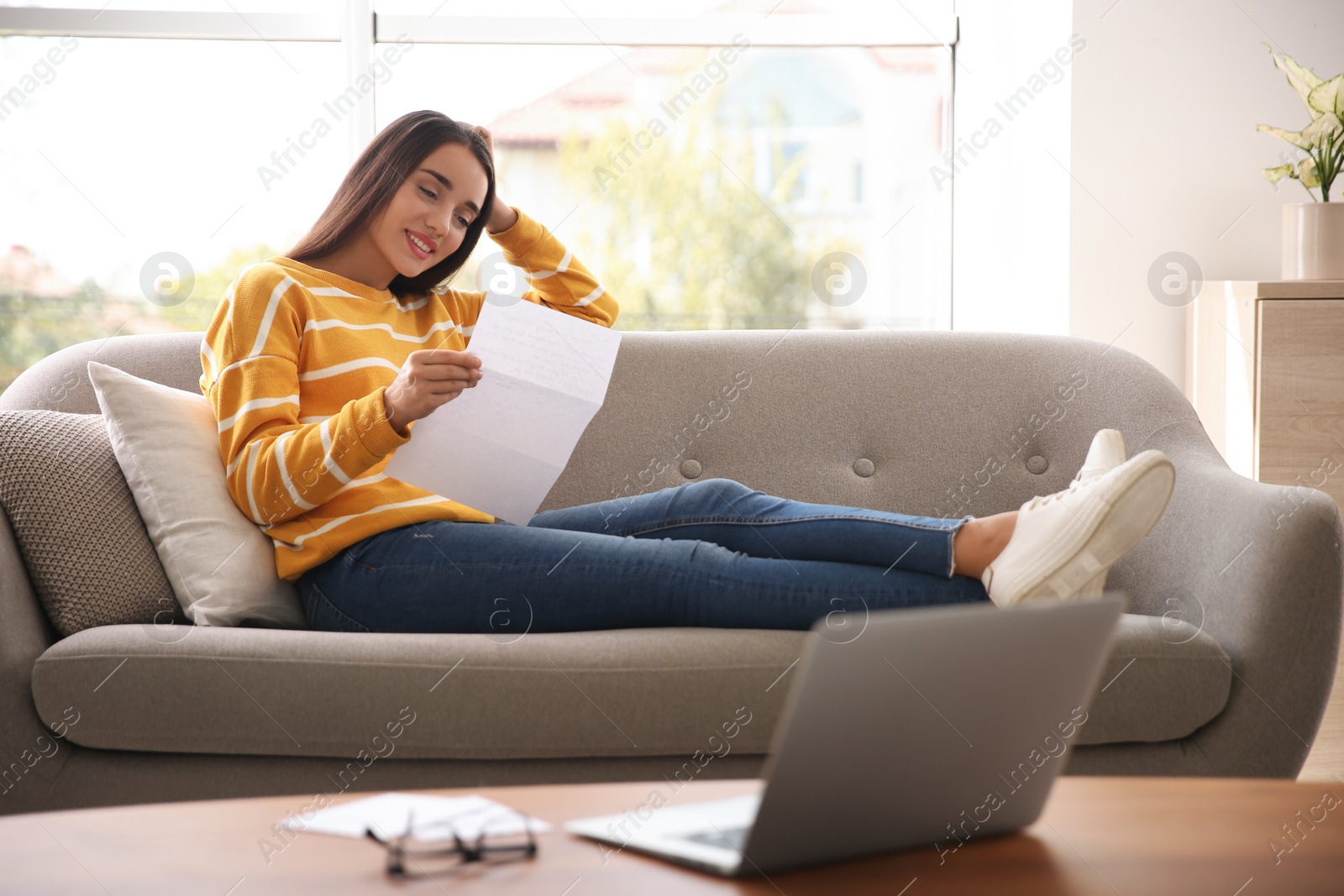 Photo of Woman reading letter on sofa at home