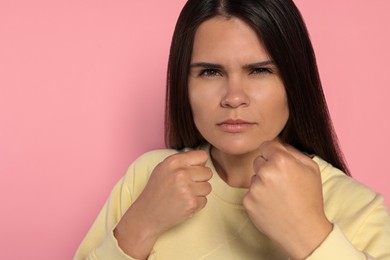 Photo of Young woman ready to fight on pink background, space for text