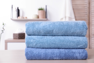 Stack of fresh towels on table in bathroom