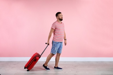 Man with suitcase near color wall. Vacation travel
