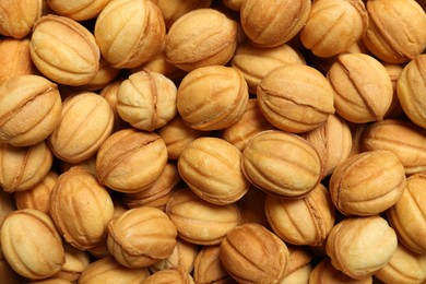 Delicious nut shaped cookies with boiled condensed milk as background, top view