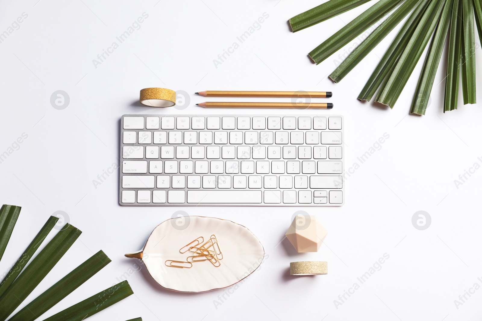 Photo of Creative flat lay composition with tropical leaves, stationery and computer keyboard on white background