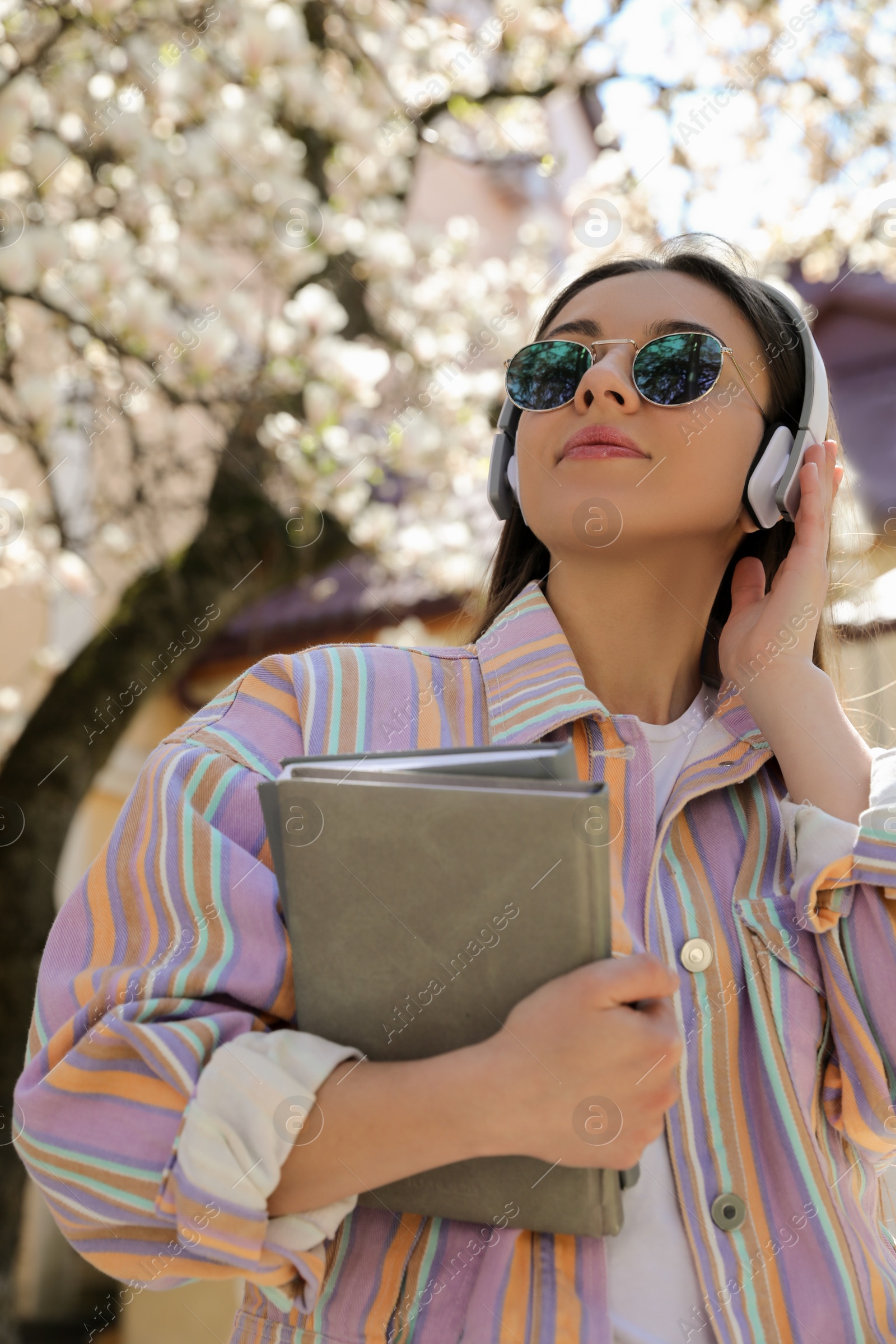 Photo of Young woman listening to audiobook on city street