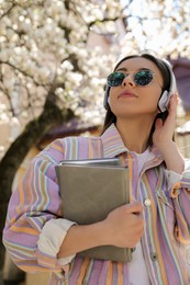 Photo of Young woman listening to audiobook on city street