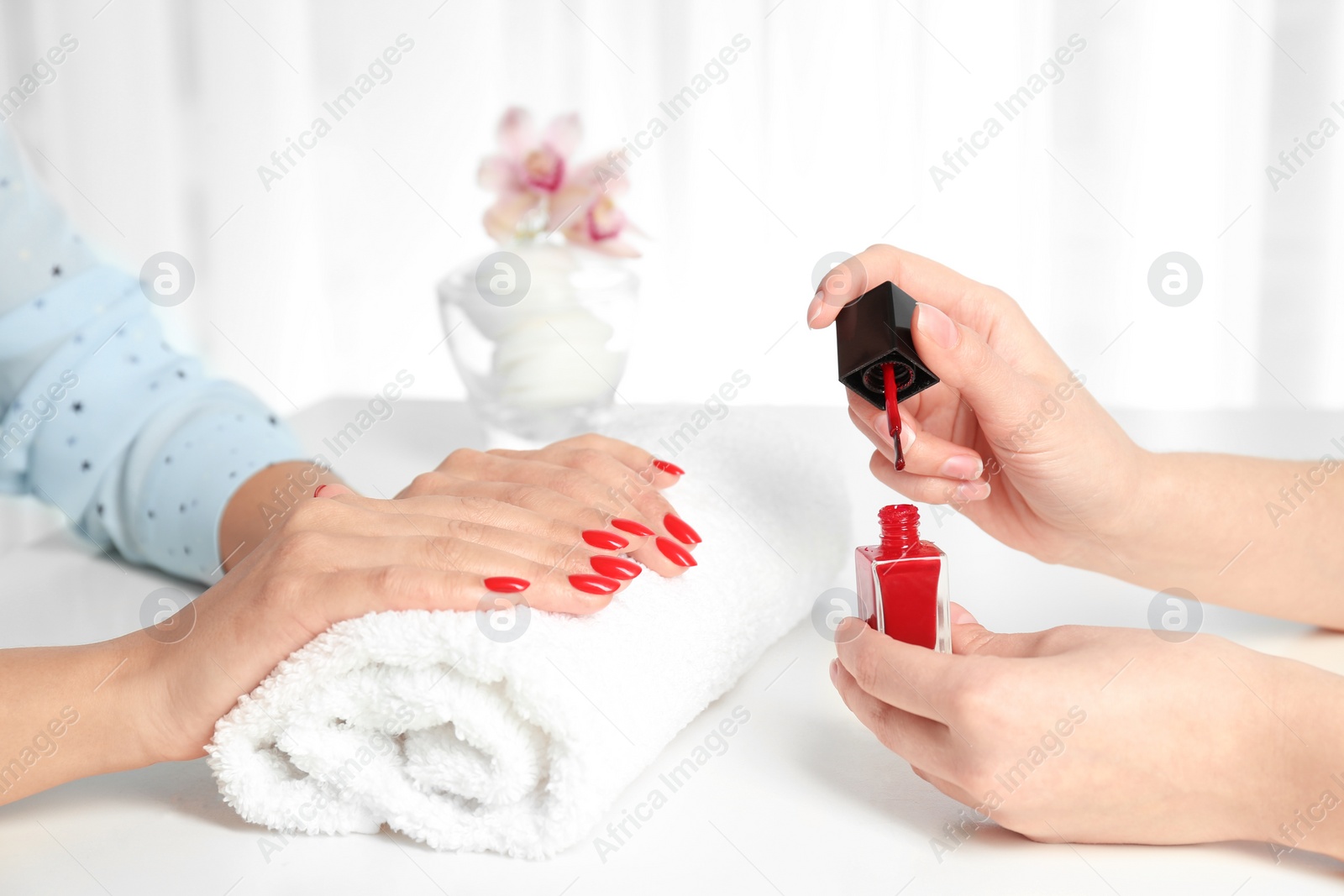 Photo of Manicurist painting client's nails with bright polish in salon, closeup