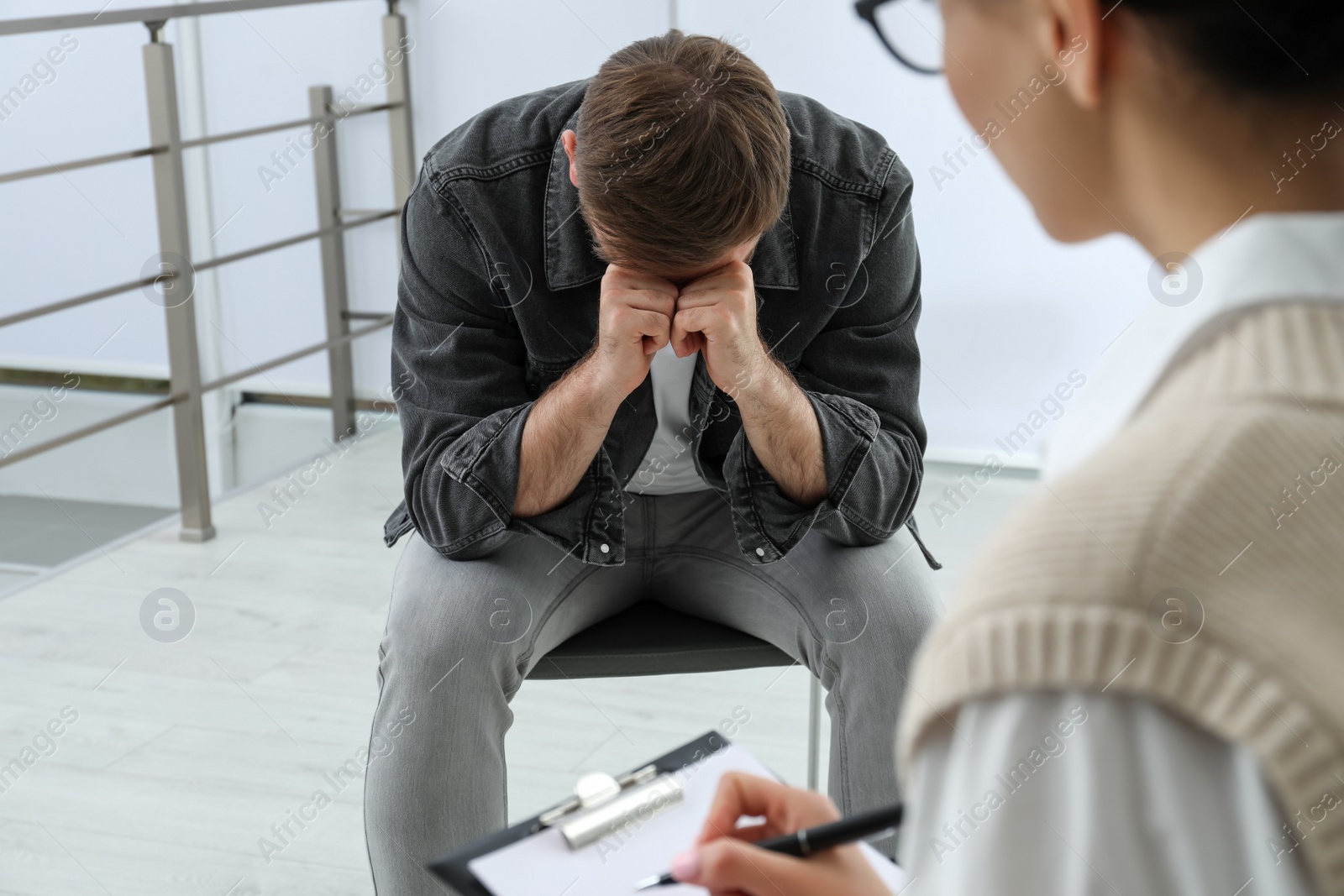 Photo of Psychotherapist working with drug addicted young man indoors