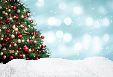 Image of Beautifully decorated Christmas tree and snow on light blue background, space for text. Bokeh effect